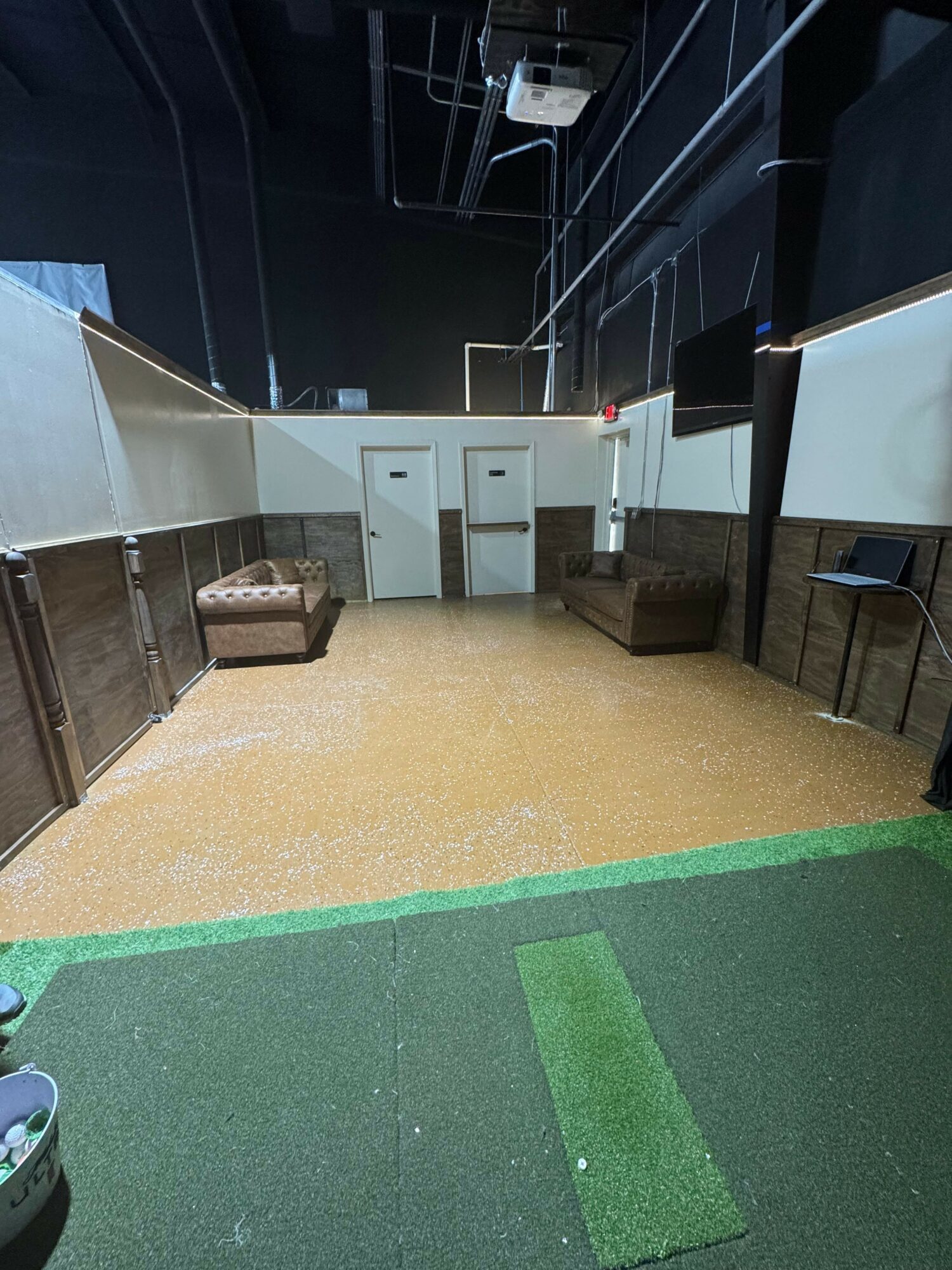 Indoor space with two doors, seating, and a carpeted area, possibly a recreational or lounge area.