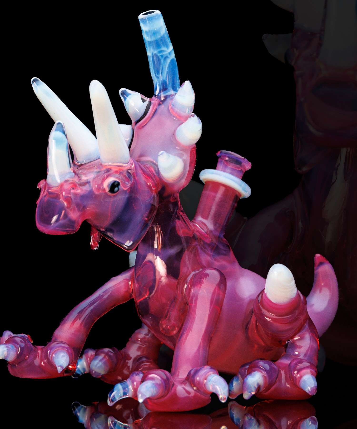 Glass sculpture of a pink and purple dragon with white and blue accents, detailed features, and multiple horns.