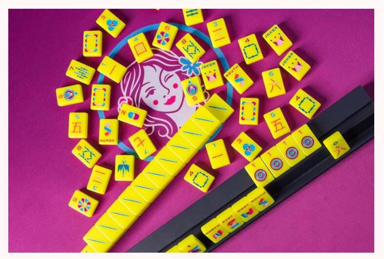 Collection of yellow domino tiles with colorful symbols, a black domino holder, and a pink background.