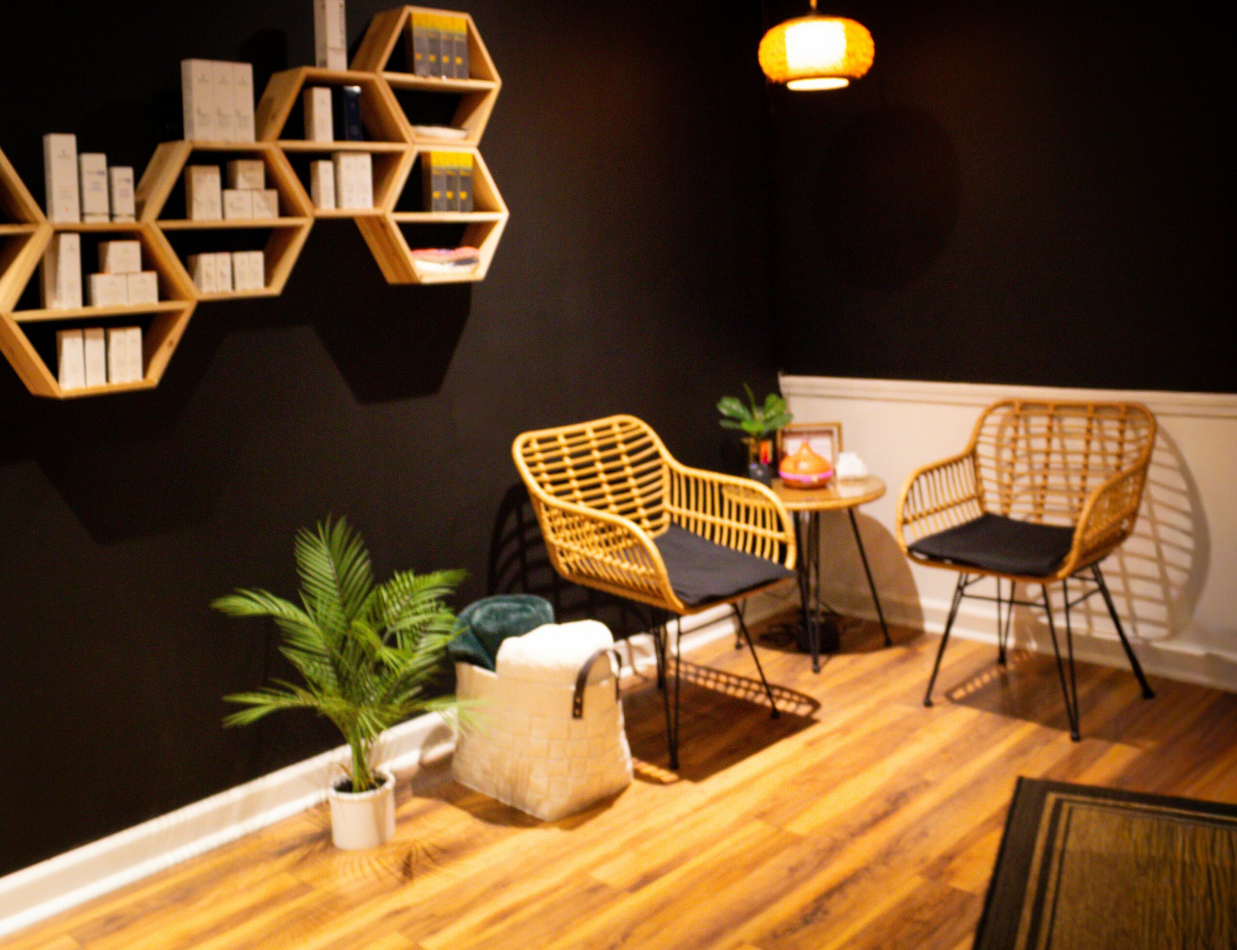 Cozy seating area with two wicker chairs, a small round table, a potted plant, and decorative wall shelves.