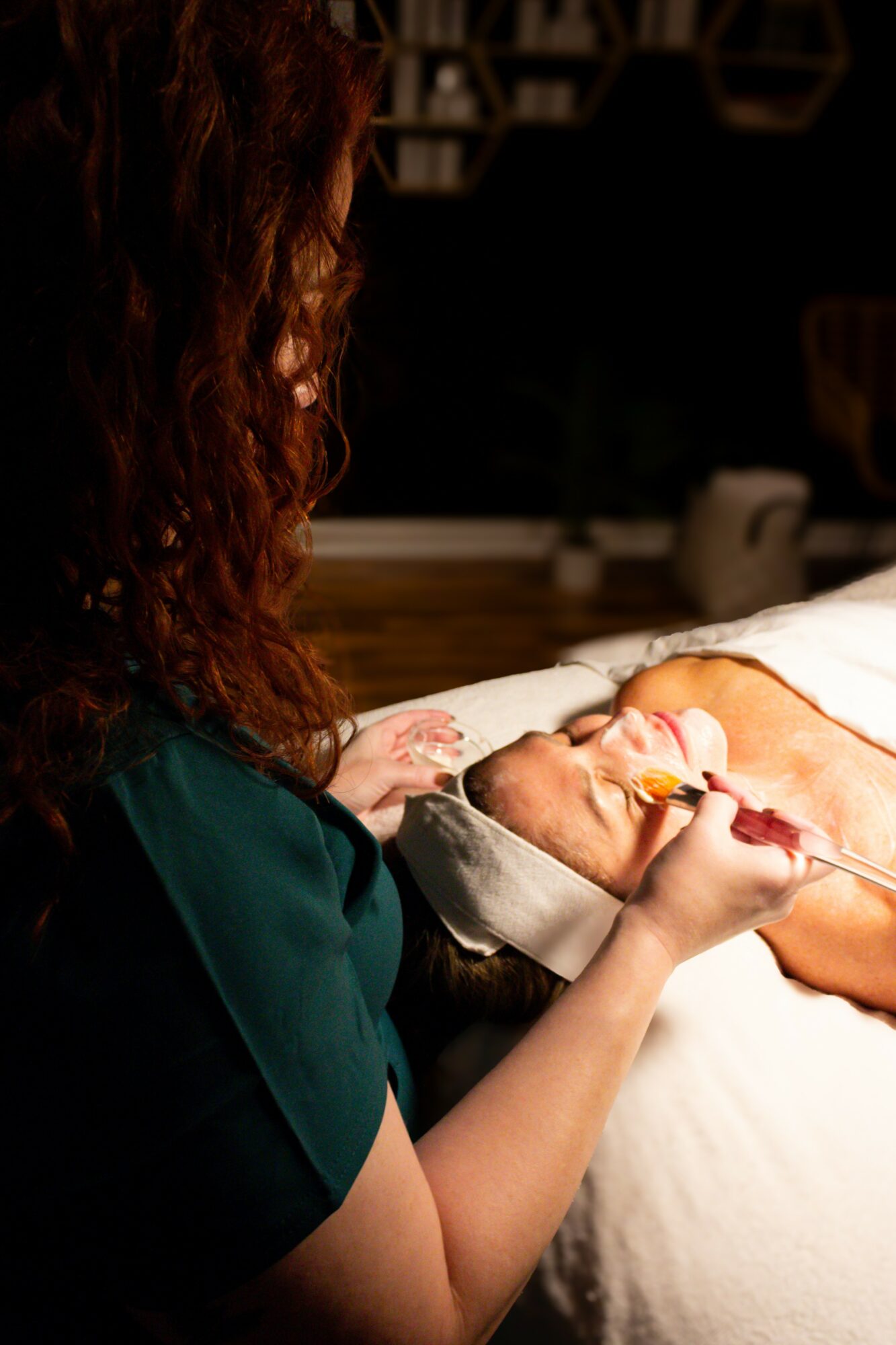 Person with curly hair holding a newborn baby with a nasal tube in a hospital bed.