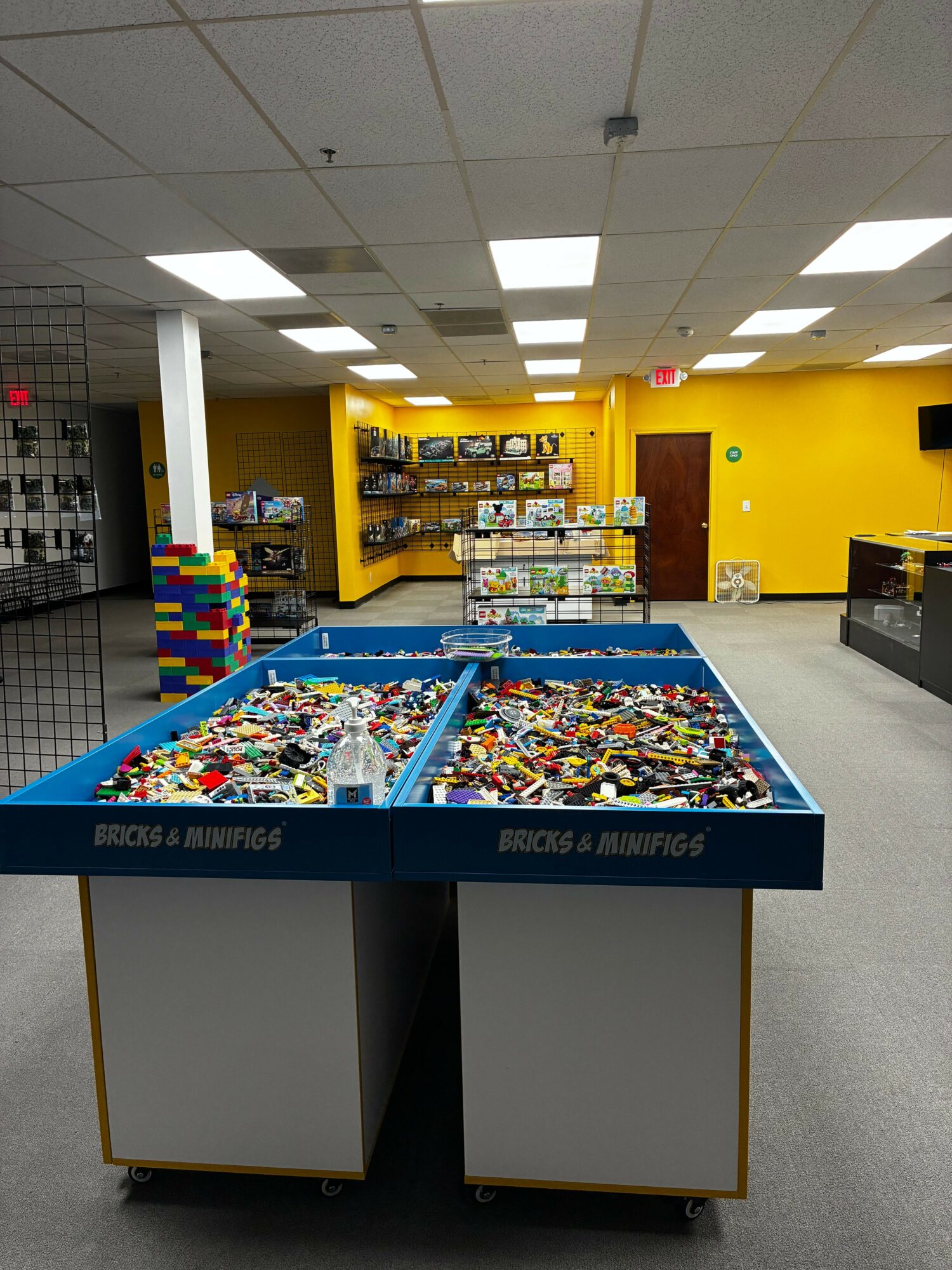 Toy bricks and building blocks in a store display with yellow walls and shelves in the background.