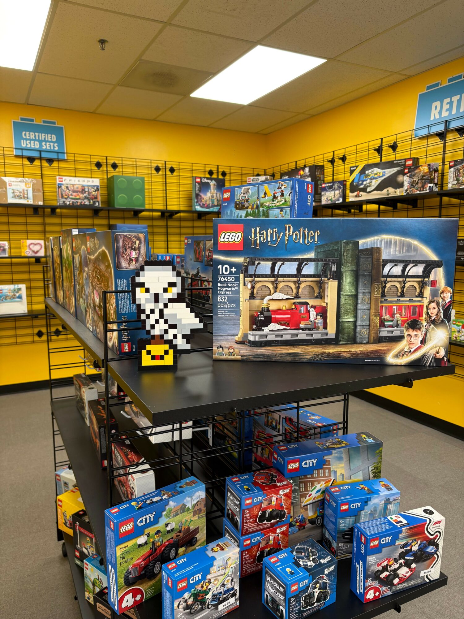 Display of LEGO Harry Potter sets with a pixel art ghost figure on a black table in a store aisle.