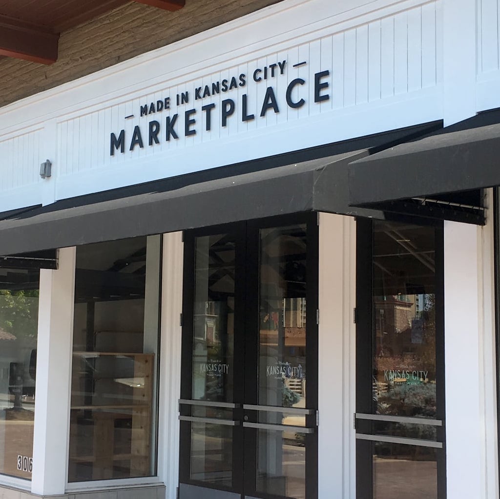 Storefront with sign reading 'Made in Kansas City Marketplace' above entrance, glass doors and windows, modern design.