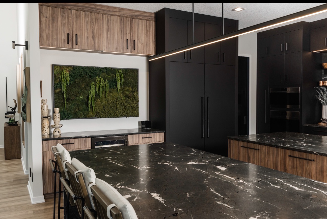 Modern kitchen with black and wood cabinets, marble countertop, and a large window with greenery view.