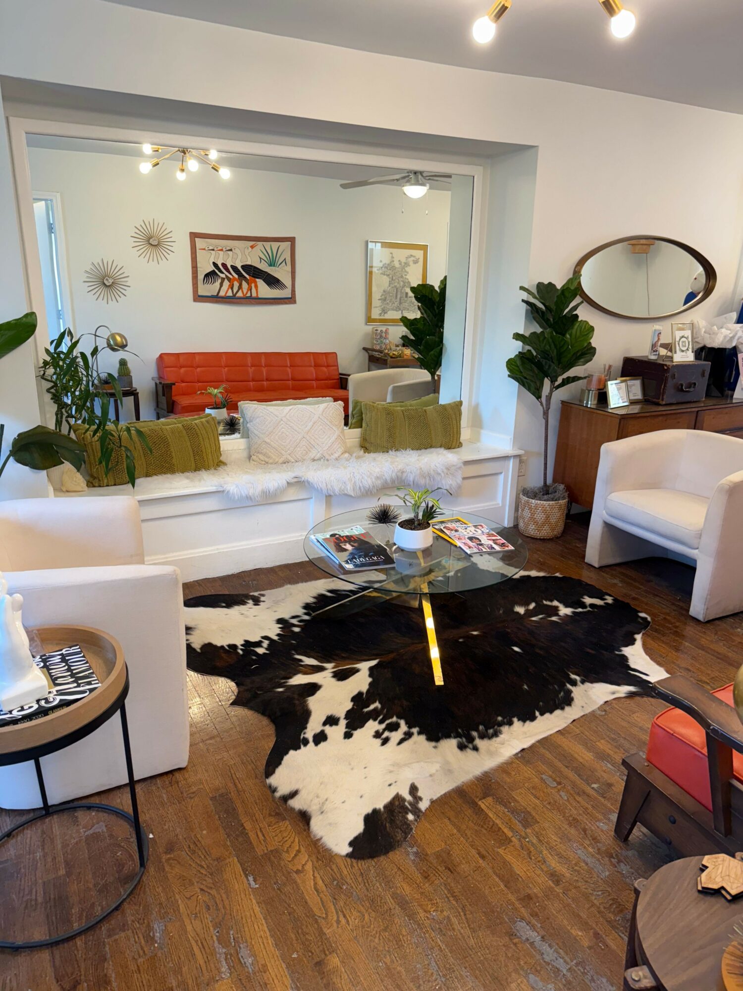 Living room with white sofa, black and white cowhide rug, and wooden floor, viewed from doorway.