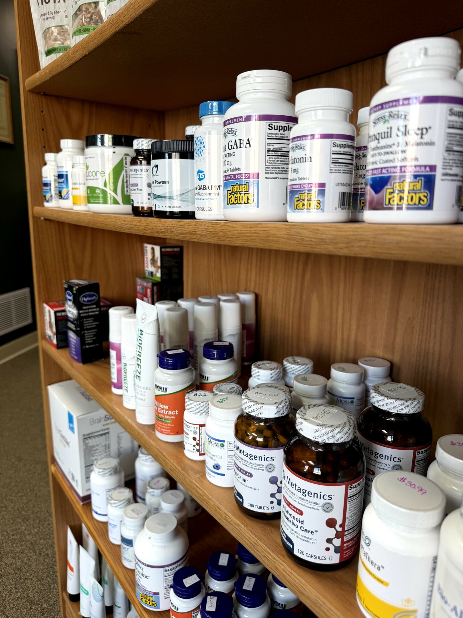 Shelves filled with various supplement bottles and containers in a store, organized by size and type.