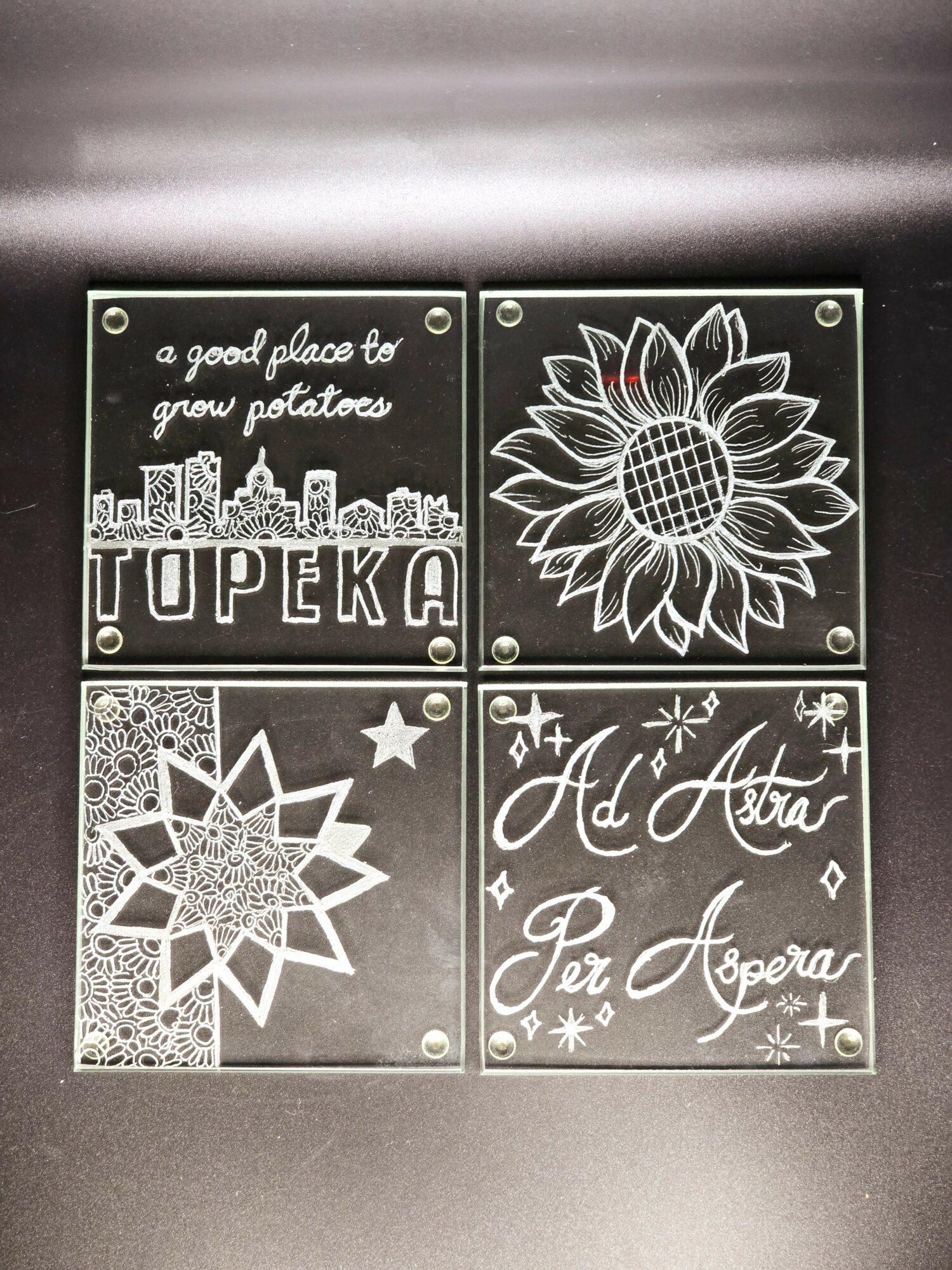 Four decorative tiles with text and floral designs, arranged in a 2x2 grid, on a dark background.