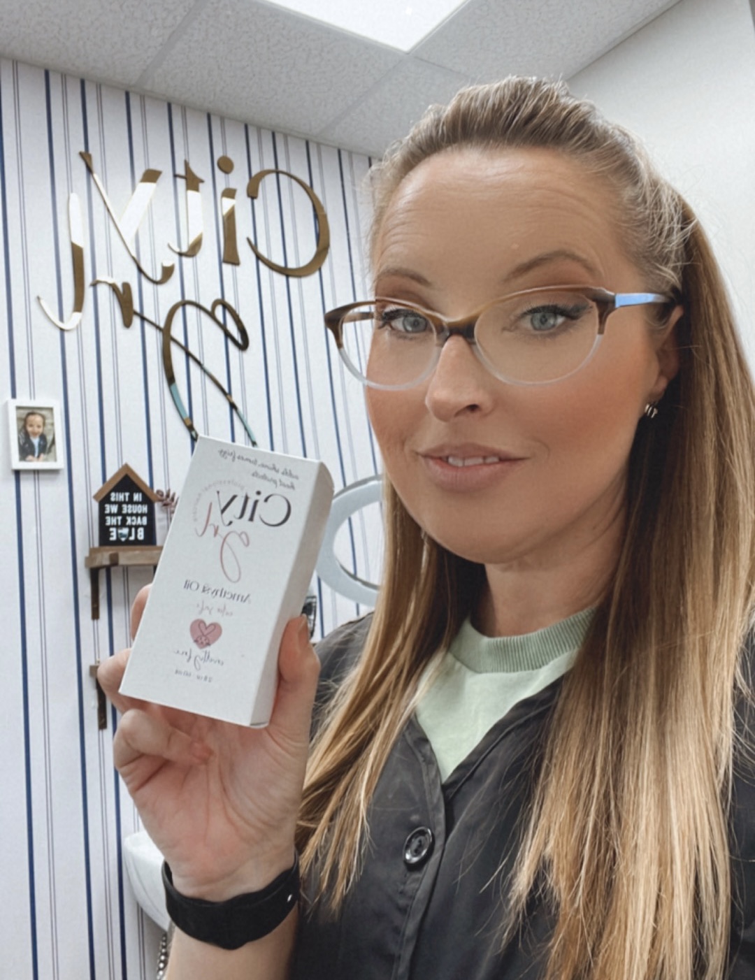 Woman with glasses holding a box with a heart symbol, standing in front of a striped wall with text. Word count: 20