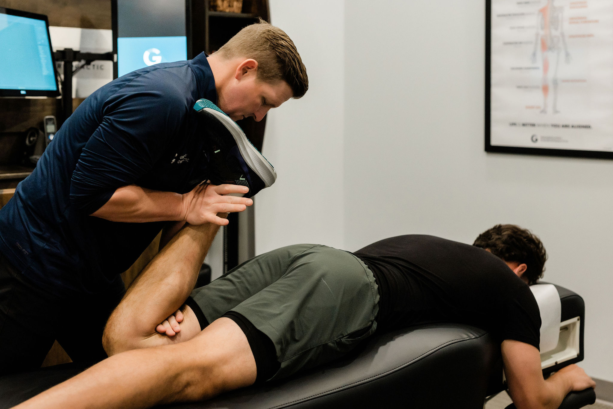 Physical therapy session with a person lying face down on a treatment table, assisted by a therapist holding their leg.