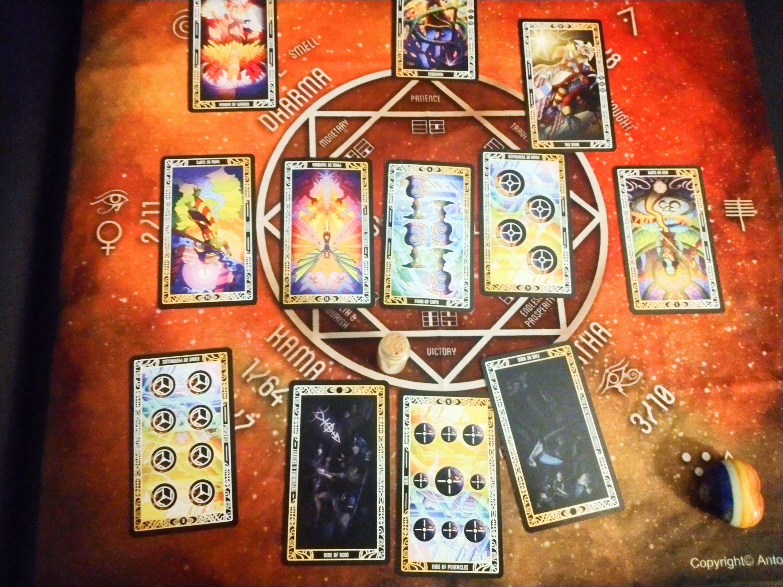 Tarot cards arranged in a circle on a red background with symbols and numbers, a candle in the bottom right corner.