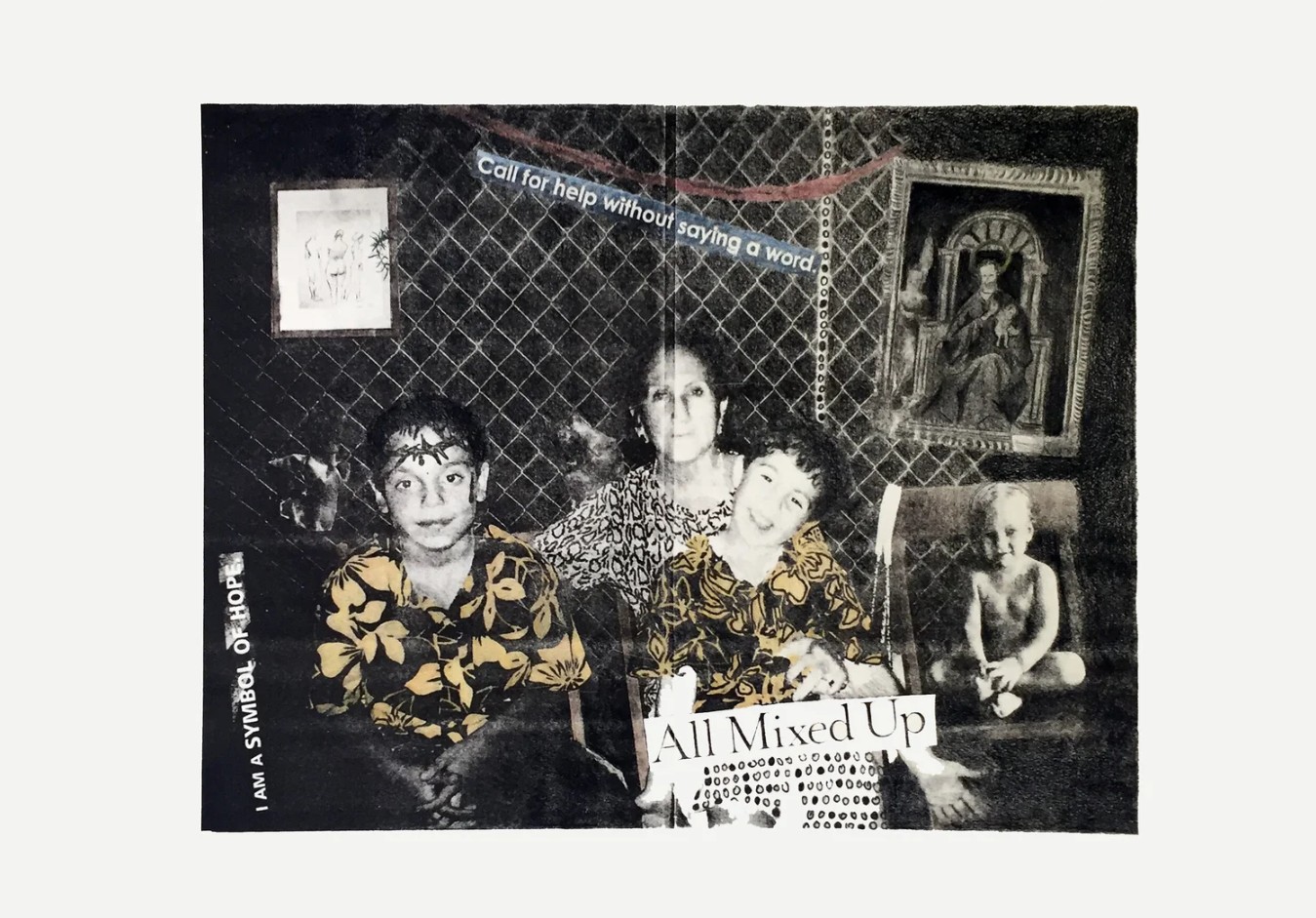 Three women sit together, holding a sign that reads 'All Mixed Up,' with a person in the background and artwork on the wall.