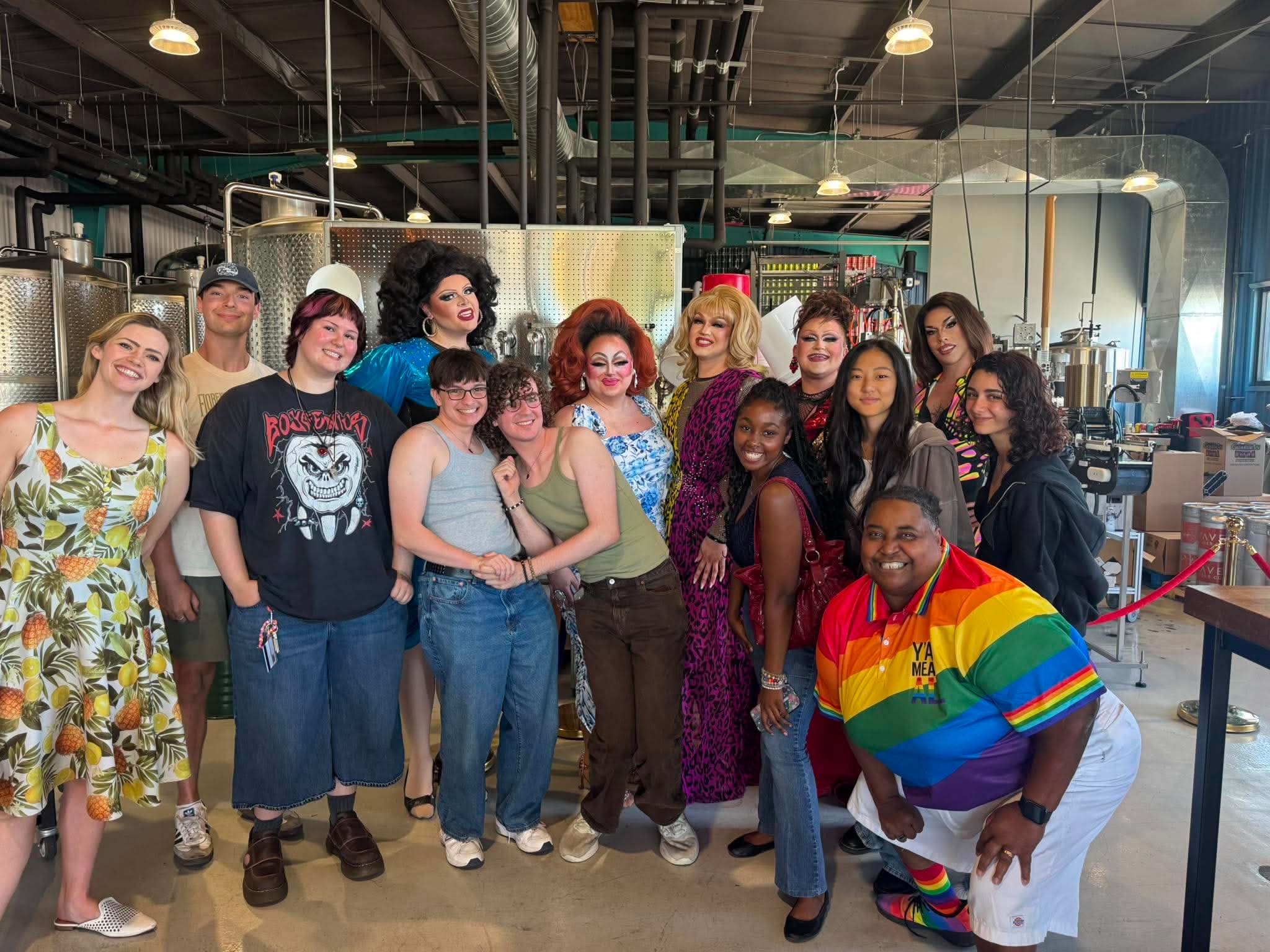 Group of diverse people posing together indoors, some smiling, in casual and colorful clothing.