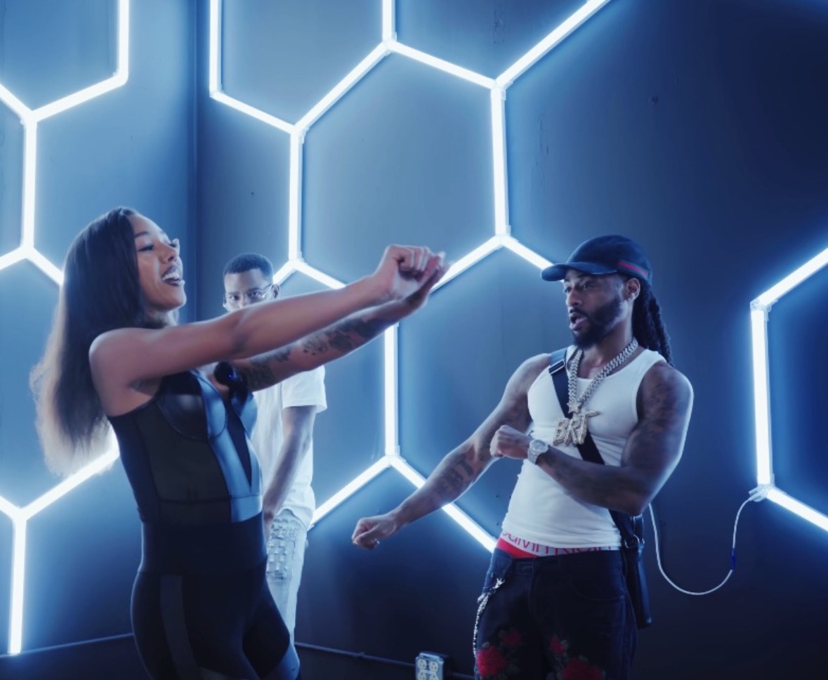 Group of people dancing in a room with illuminated hexagonal wall patterns, some smiling and moving to music.