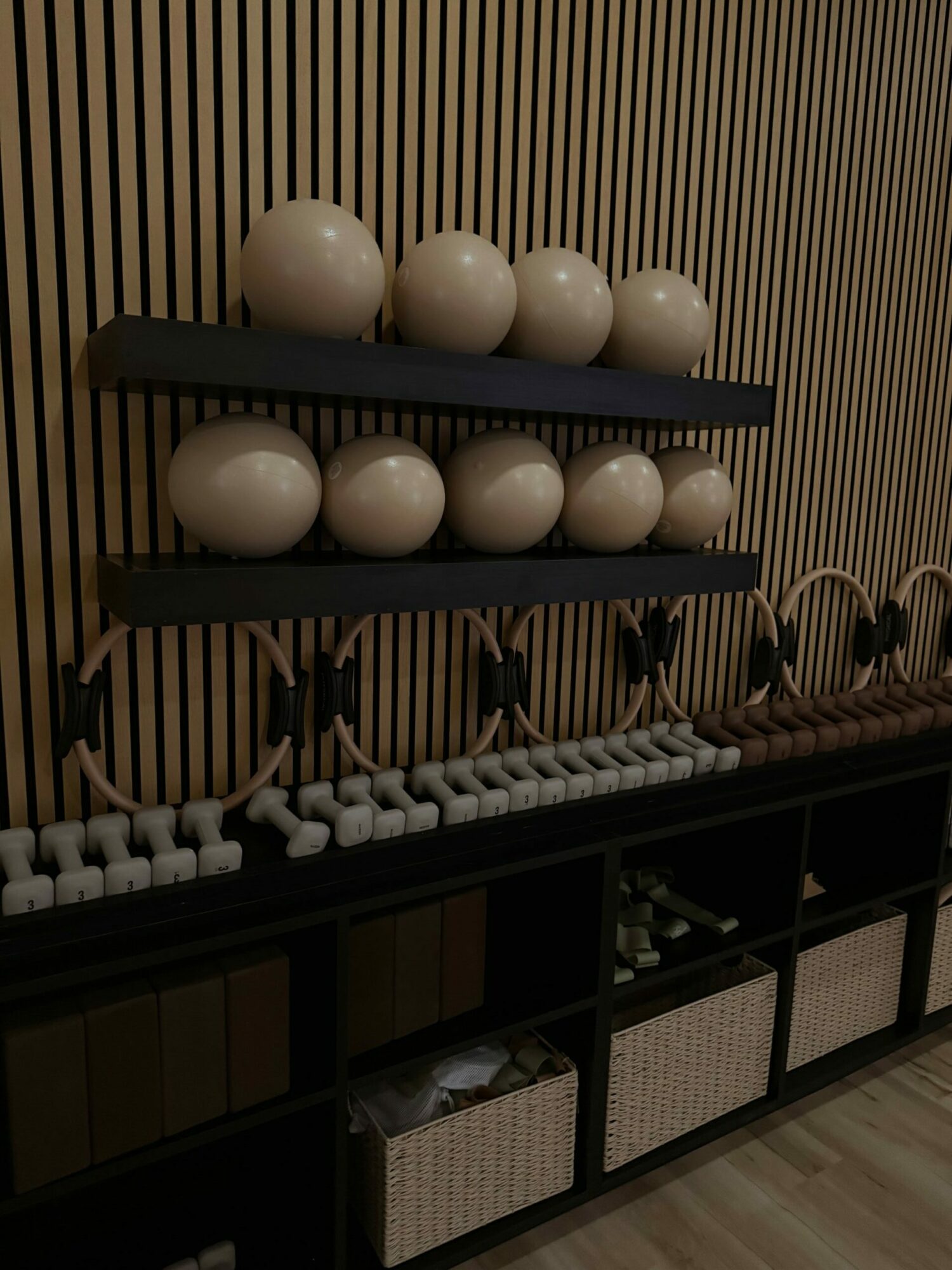 Fitness equipment with large white balls, black bars, and various workout tools on a wooden wall background.