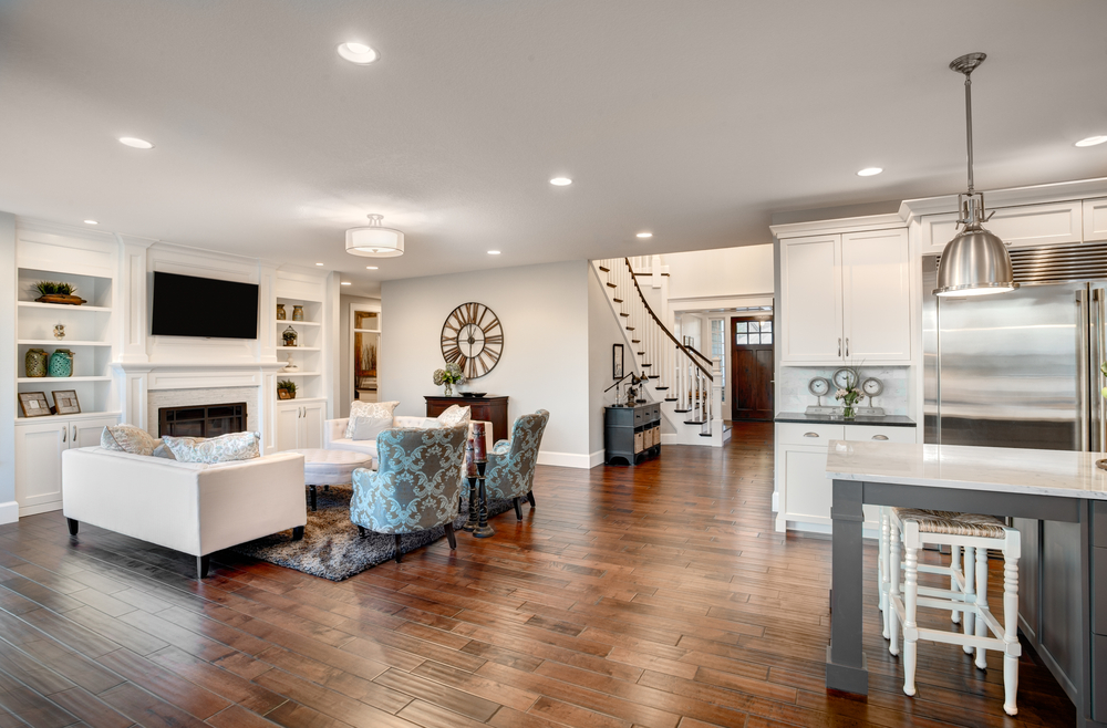 Open living room with white furniture, a fireplace, TV, and a dining area with chairs, hardwood floors, and modern decor.