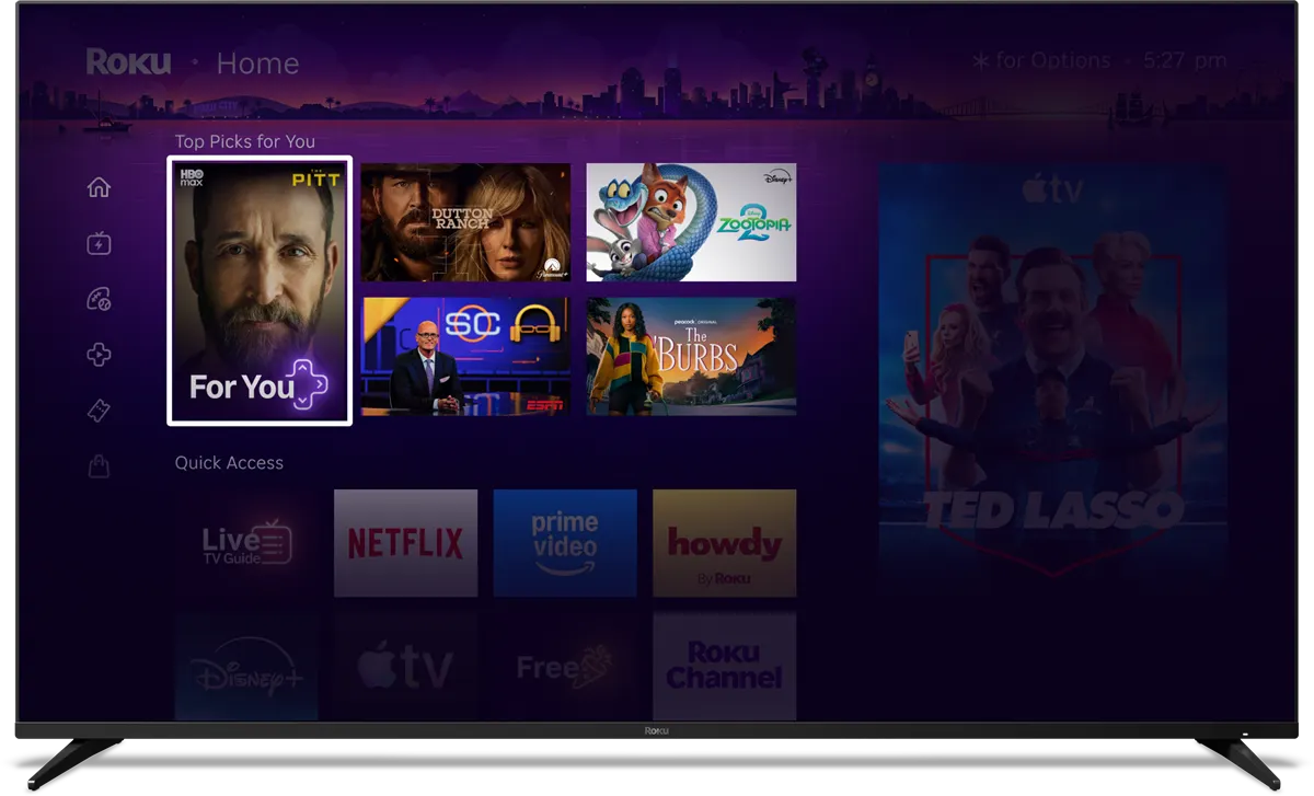 Roku home screen with various streaming app icons and a city skyline background at night.