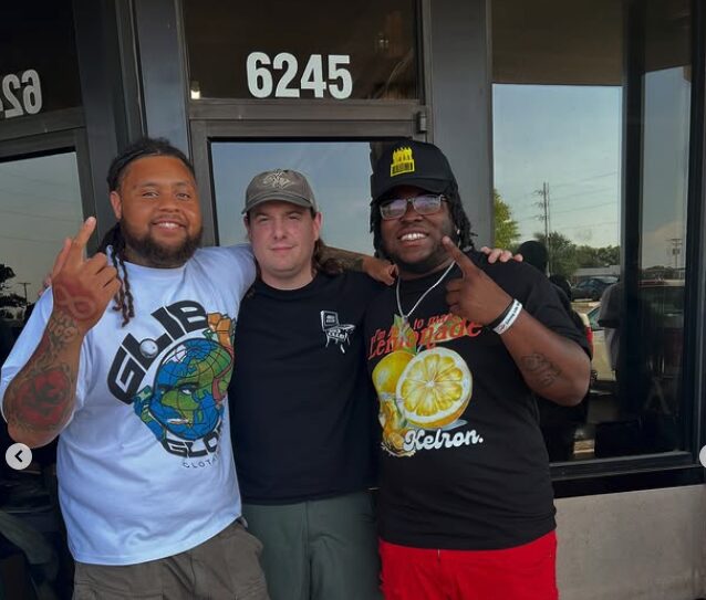 Three people standing outside a building with the number 6245, smiling and posing for the photo.