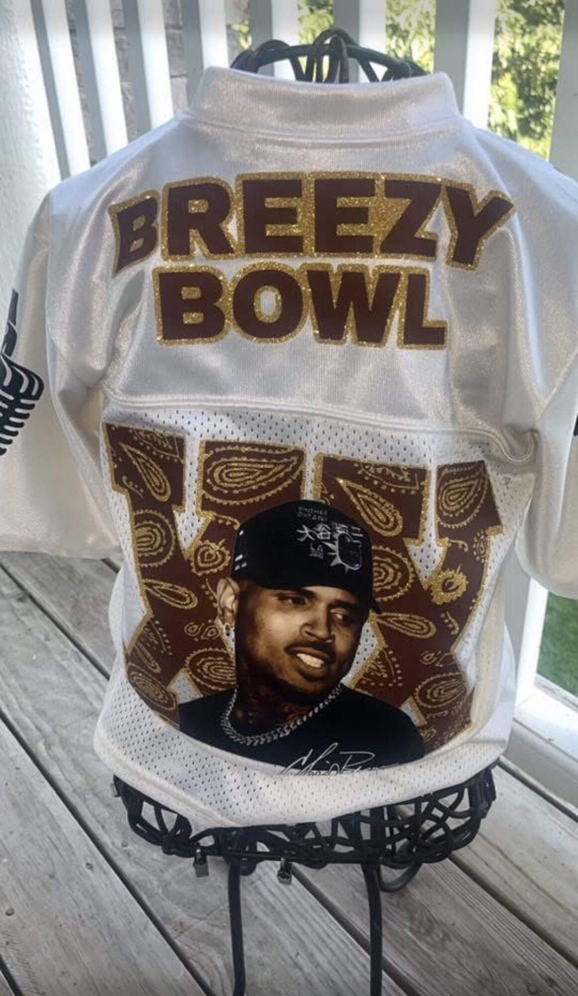 Jersey with text 'Breezy Bowl' and a photo of a man wearing a cap, displayed on a stand near a window.