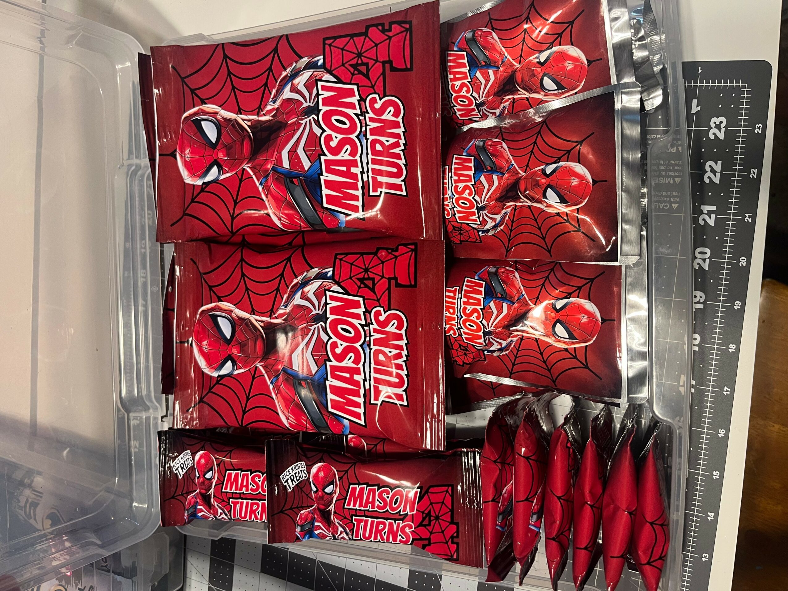 Spider-Man themed candy boxes and pens arranged on a surface, with a ruler visible on the right side.