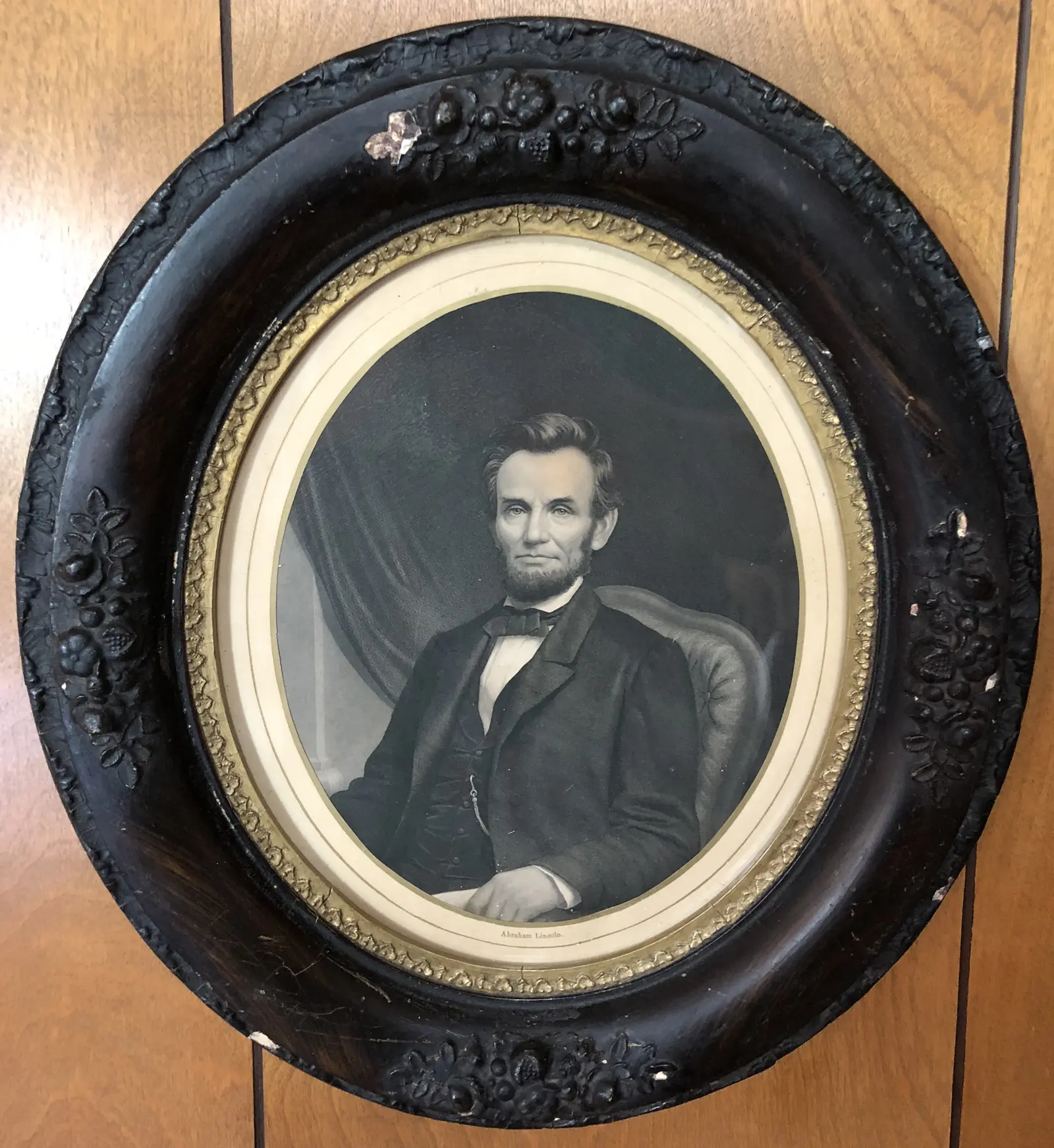 Oval framed black-and-white portrait of a man in formal attire, seated with a serious expression, against a dark background.
