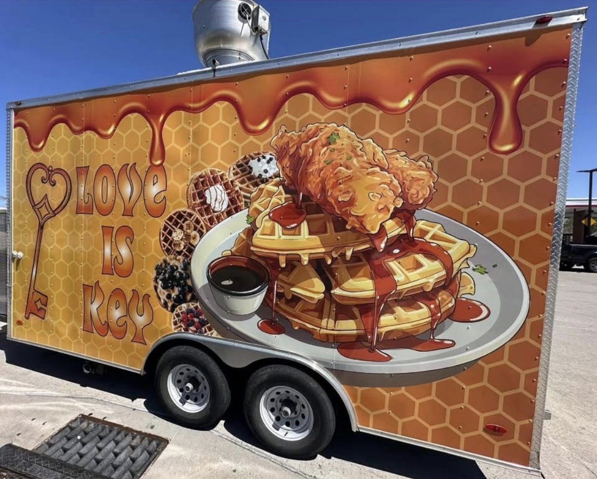 Food truck with a large waffle, fried chicken, and syrup, honeycomb background, and the phrase 'Love is Key' with a heart.