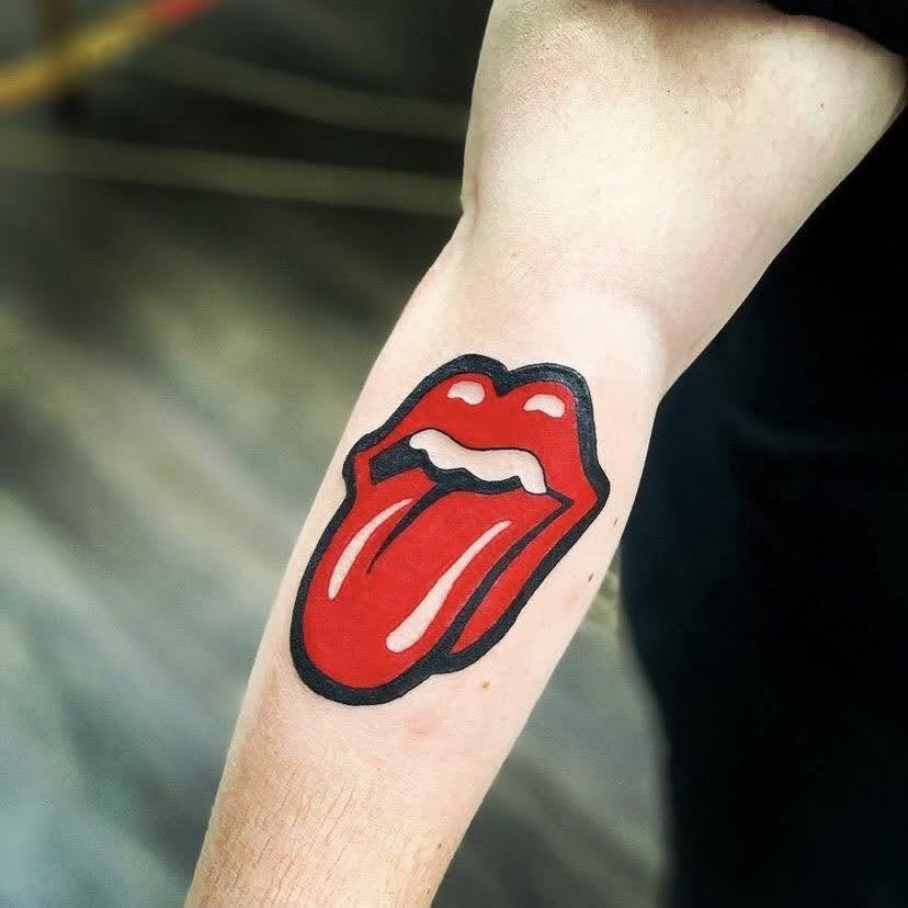 Tattoo of a red tongue sticking out with lips, outlined in black, on person's arm.
