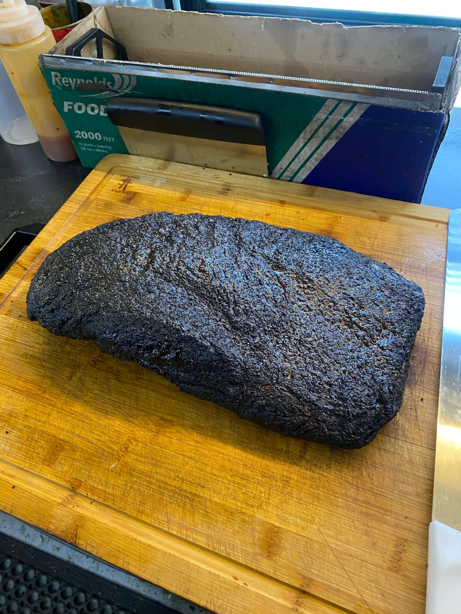 Large, dark, textured rock on a wooden cutting board in a kitchen setting.