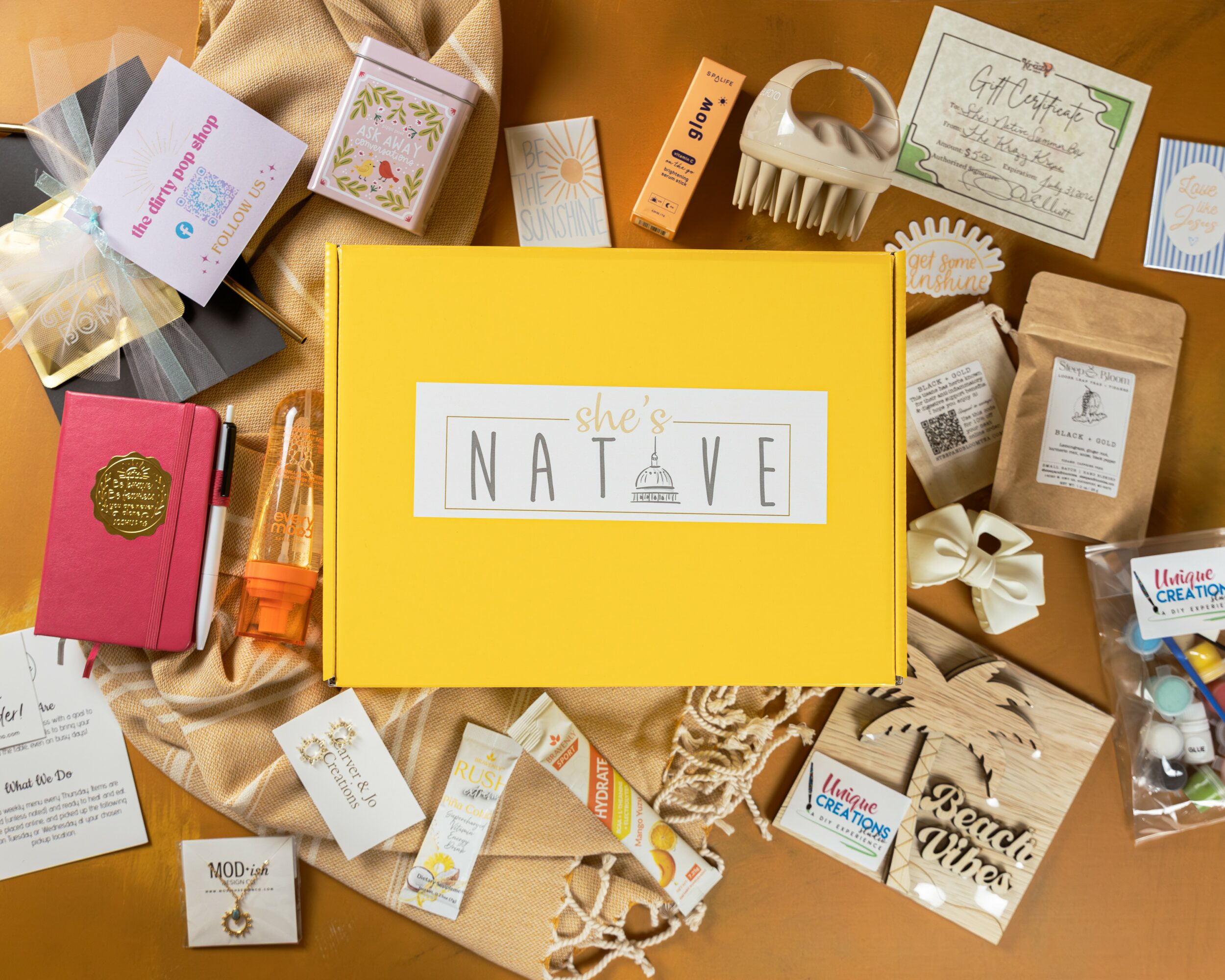 Yellow box labeled 'NATIVE' surrounded by various skincare and beauty products, packaging, and labels on a beige fabric surface.