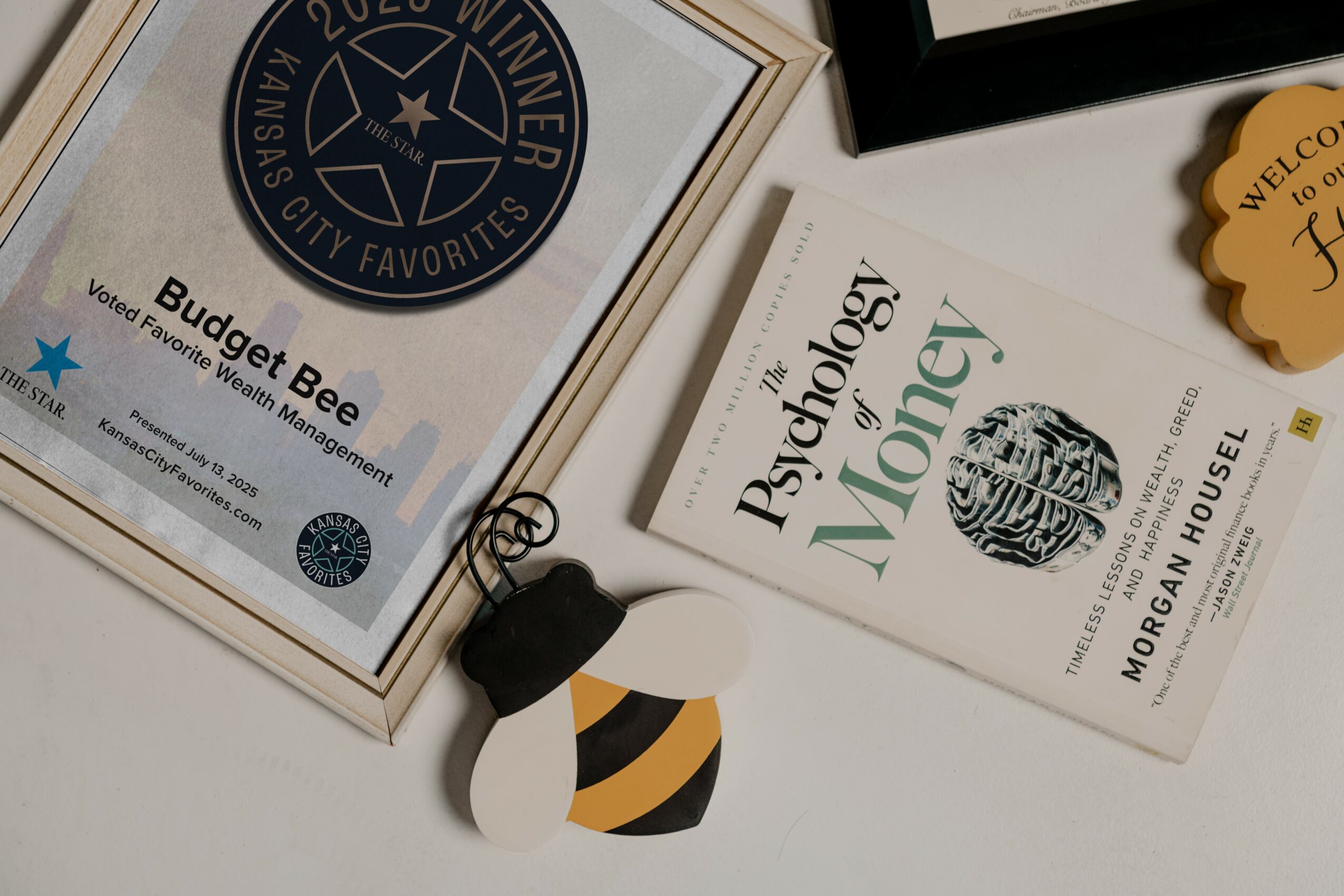 Book titled 'Psychology of Money' and a box labeled 'Budget Bee' on a white surface.