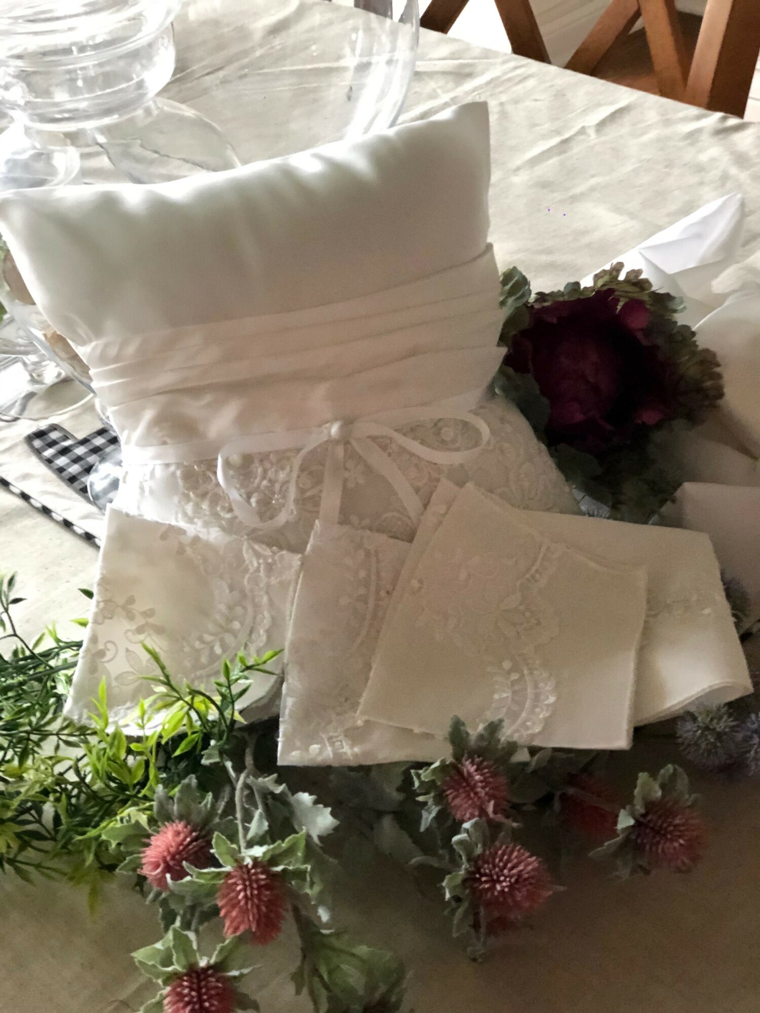 Decorative white pillow, napkins, and a bouquet of pink and green flowers on a table.