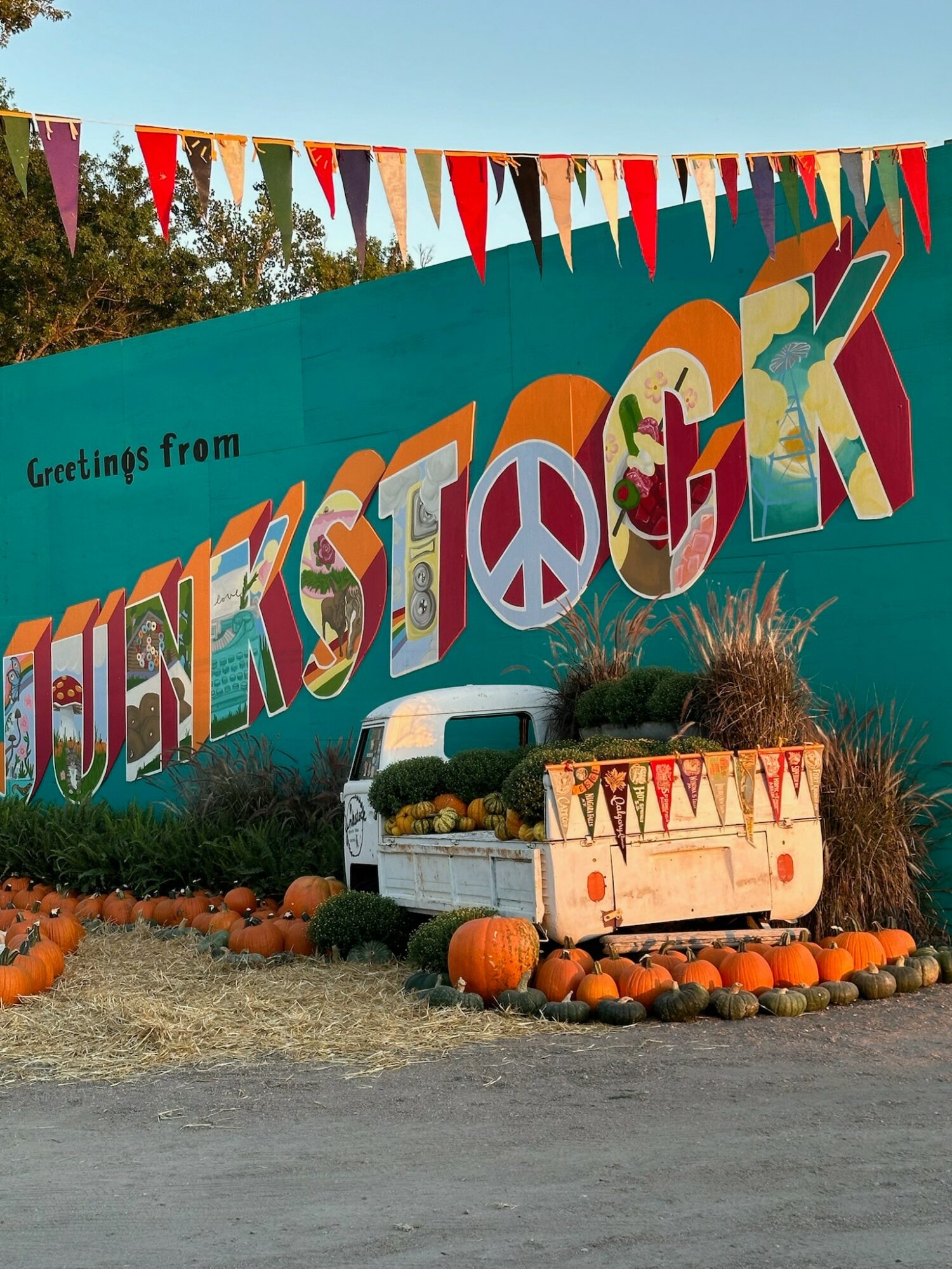 Colorful Thanksgiving banner with pumpkins and a decorated cart in front, celebrating fall and harvest season.