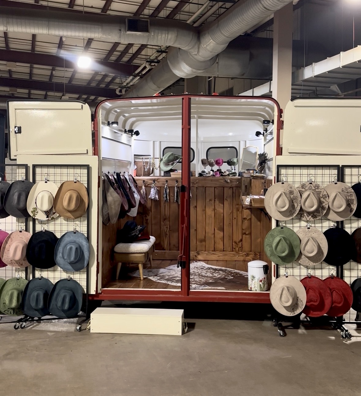 Hat display with various hats on shelves inside a store, with a wooden counter and industrial ceiling in background.