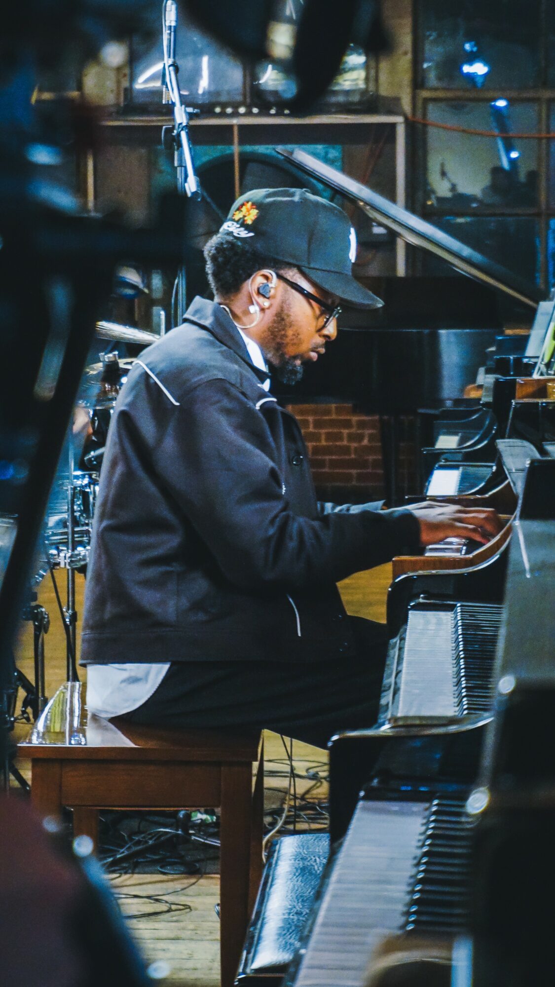 Person playing piano in a studio with equipment and shelves in background.
