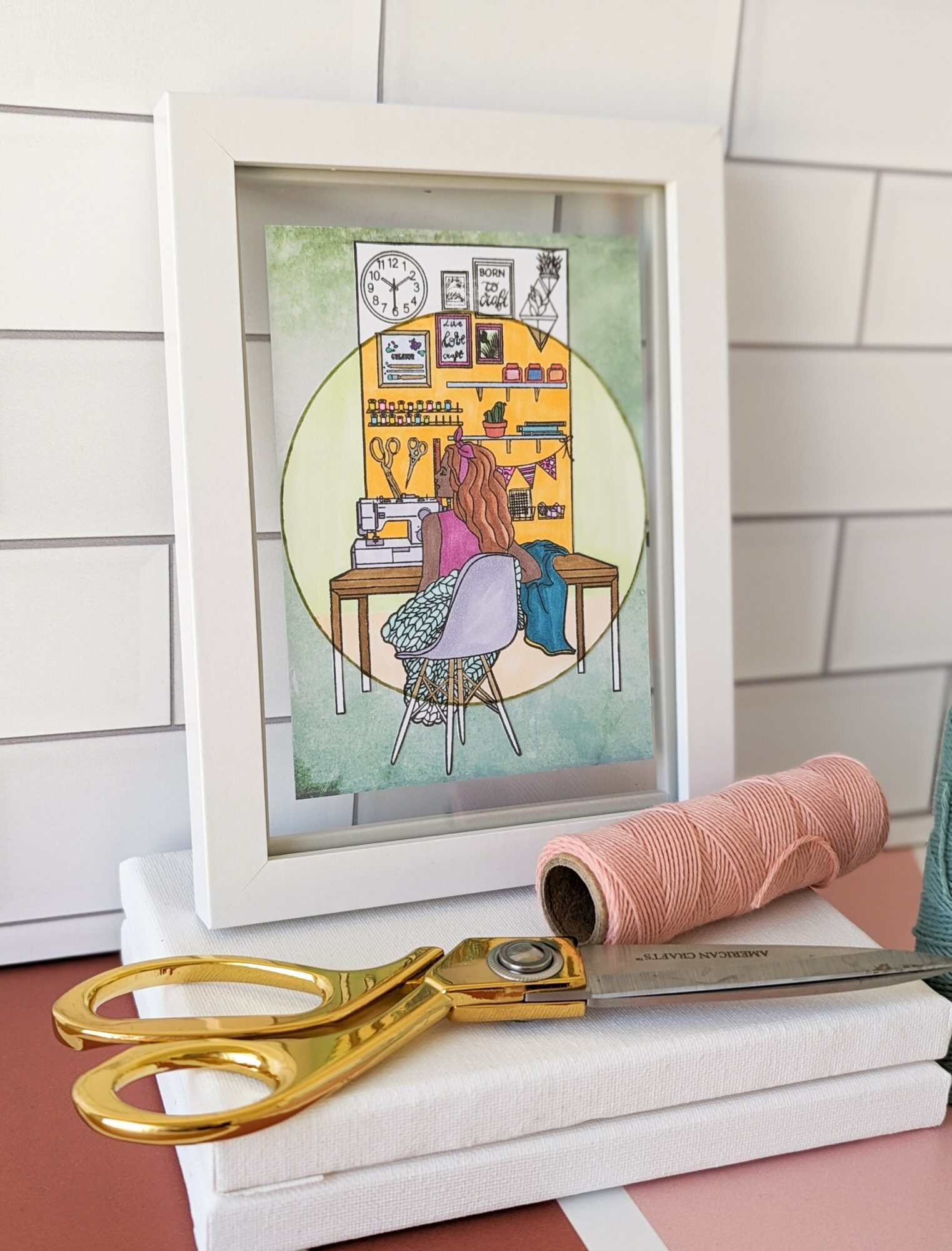 Framed illustration of a person with pink hair sitting at a desk in a room with shelves and a clock, on a white surface.