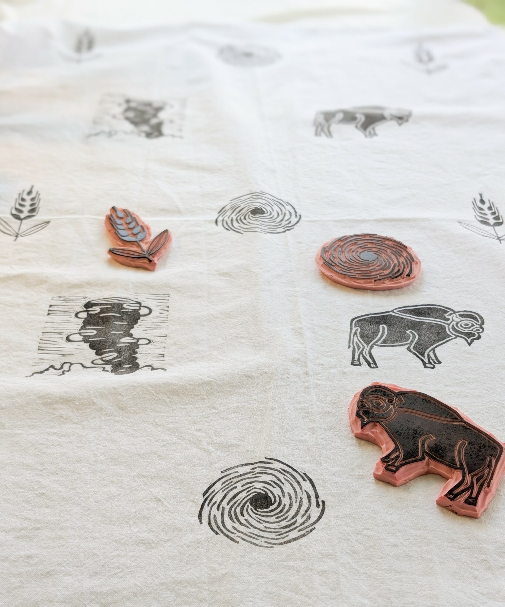 Fabric with printed animal and nature illustrations, including a bear, a lion, trees, and circular patterns, in black and brown colors.