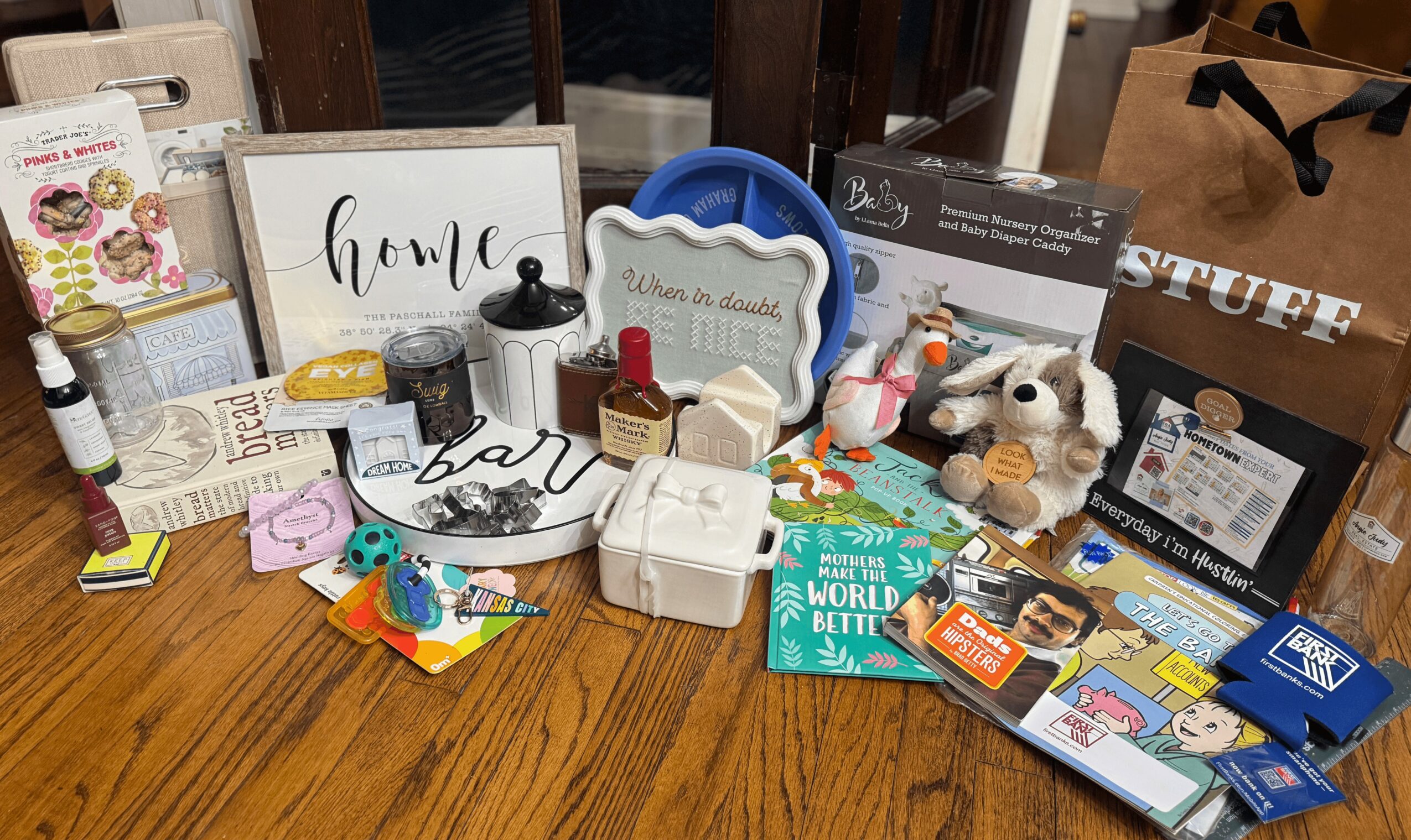 Collection of home decor, toys, and miscellaneous items on a wooden table, including signs, plush toys, and boxes.