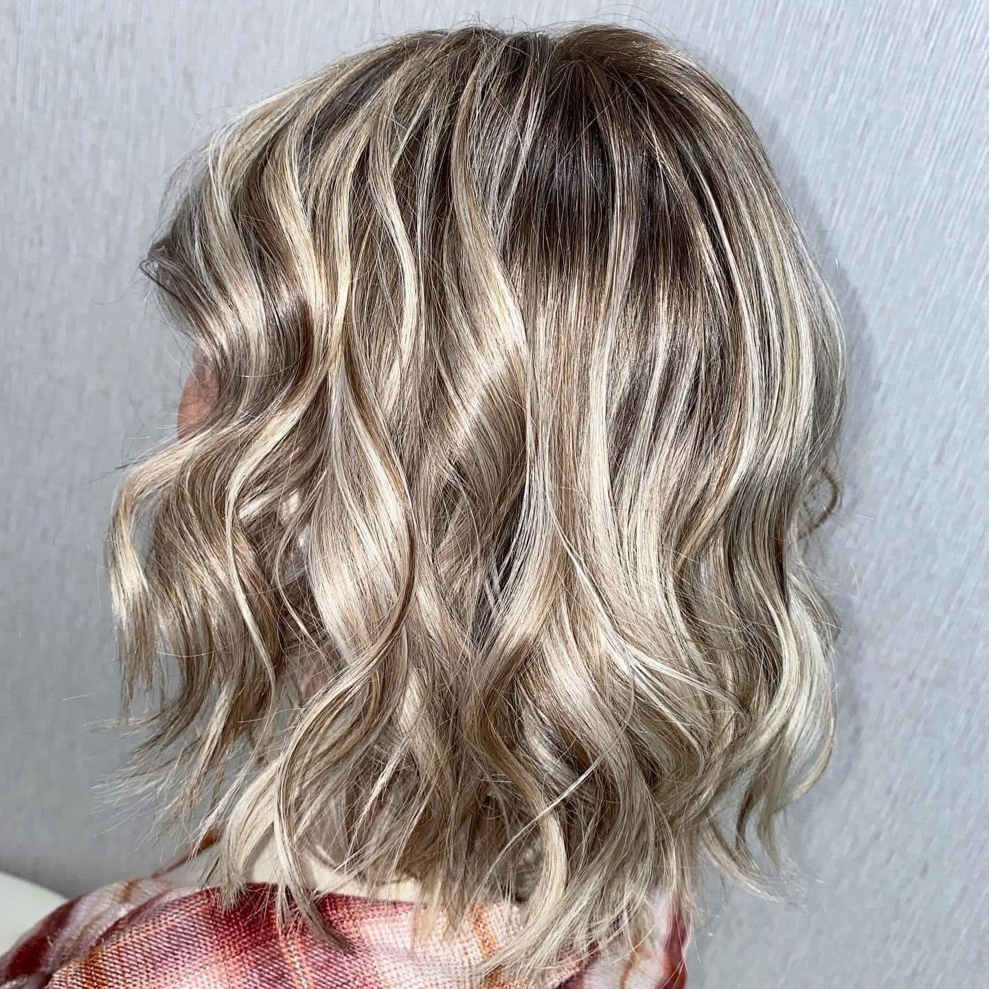 Wavy blonde hair with highlights, shoulder length, against a plain background.