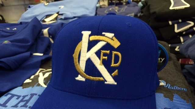 Blue baseball cap with embroidered gold and white logo featuring the letters K and F, and a curved line.
