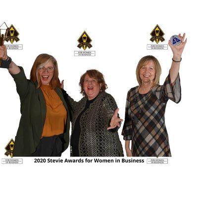 Three women smiling and holding awards at the 2020 Stevie Awards for Women in Business event.