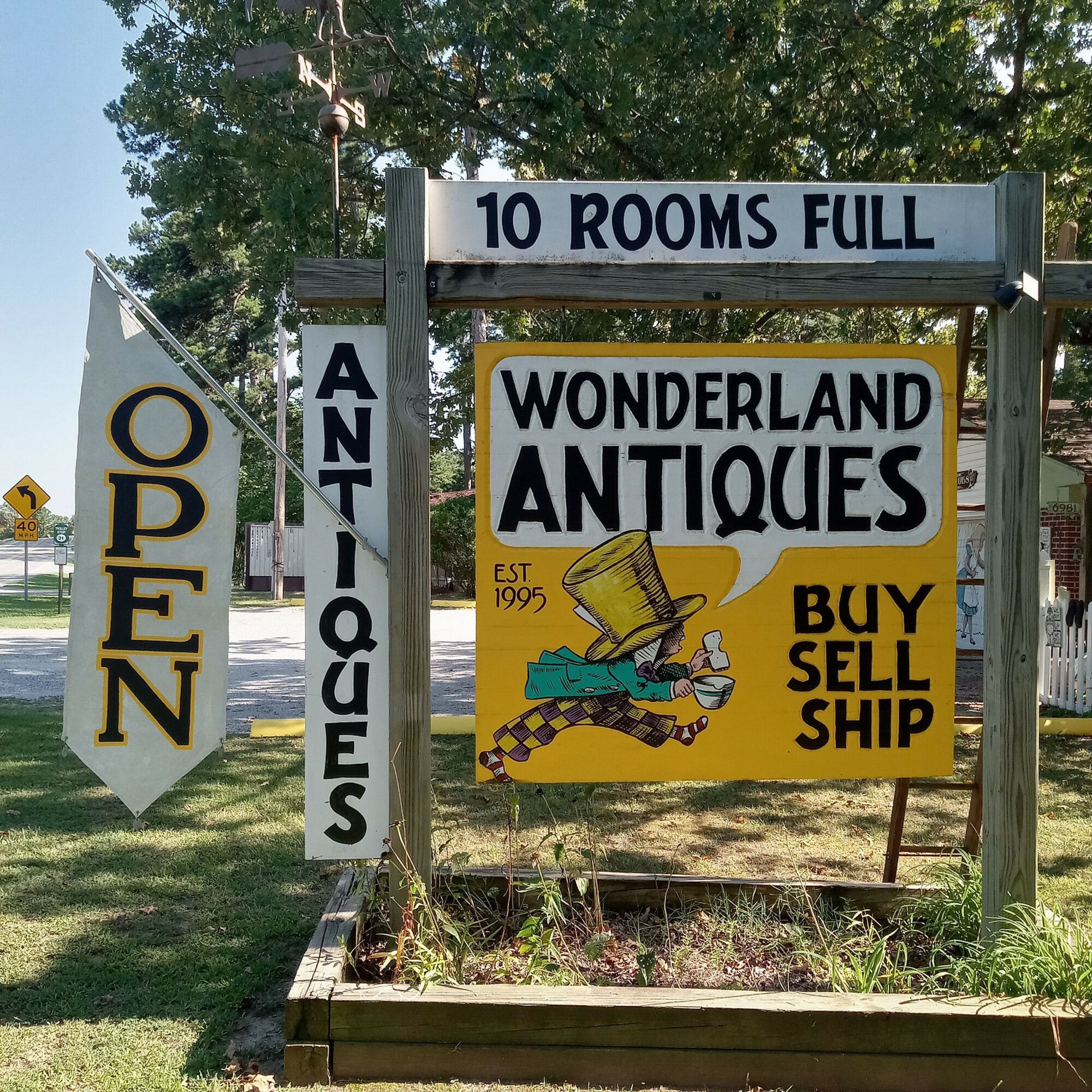 Signboard advertising antique shop with a yellow background, a person, and text about buying and selling antiques.