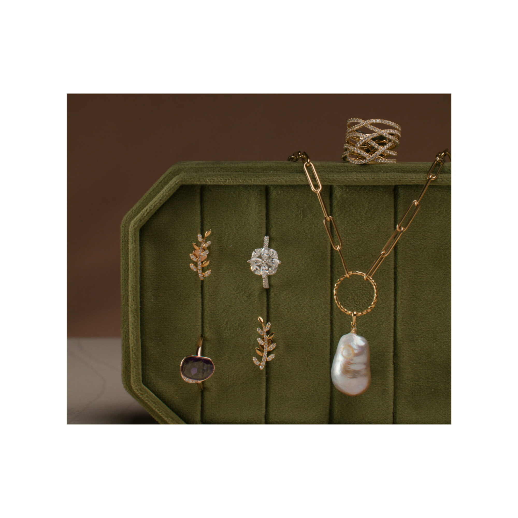 Jewelry display with necklaces and pendants in a green box, against a brown background.