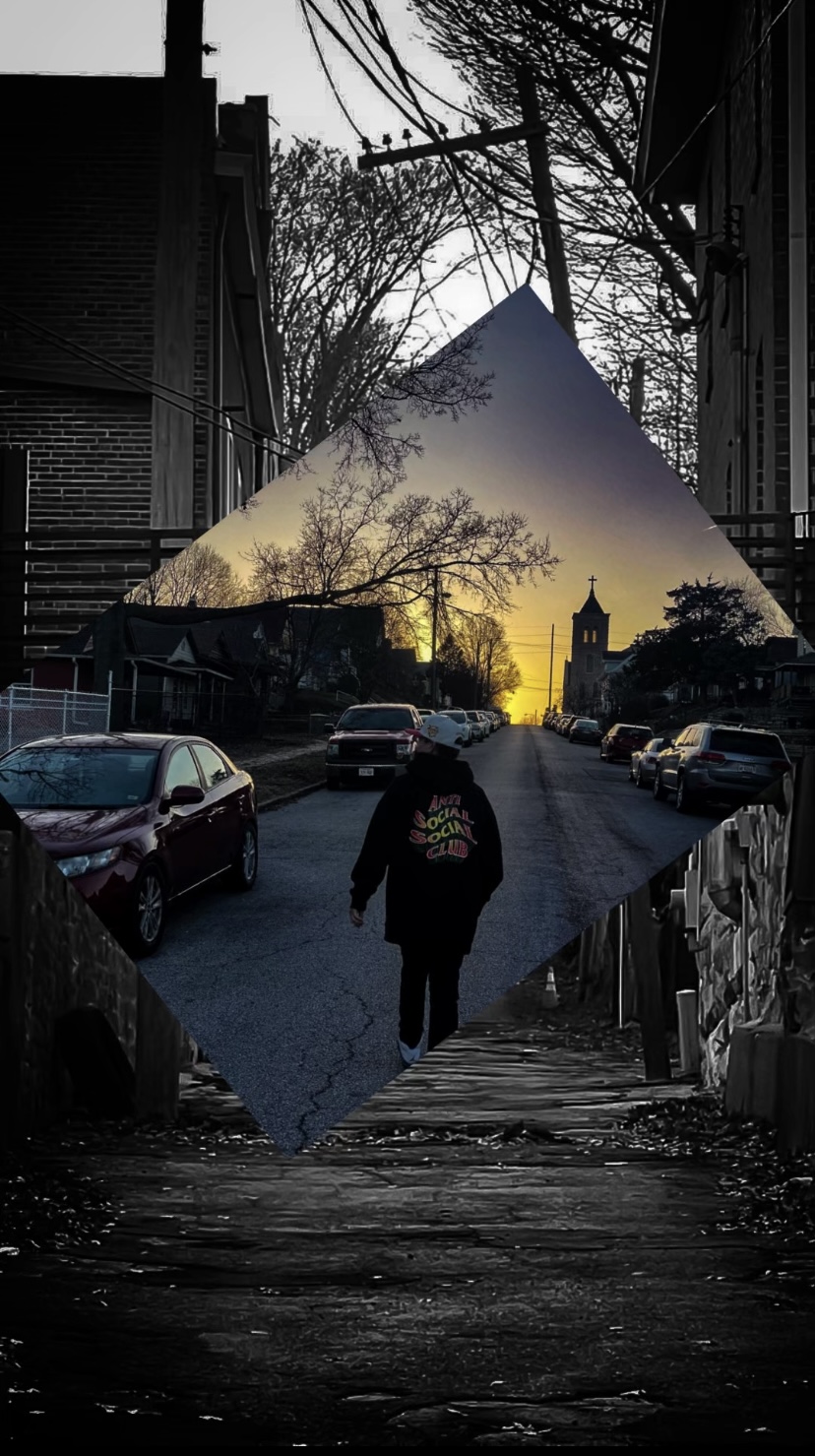 Person walking on a city street during sunset with buildings and cars around.