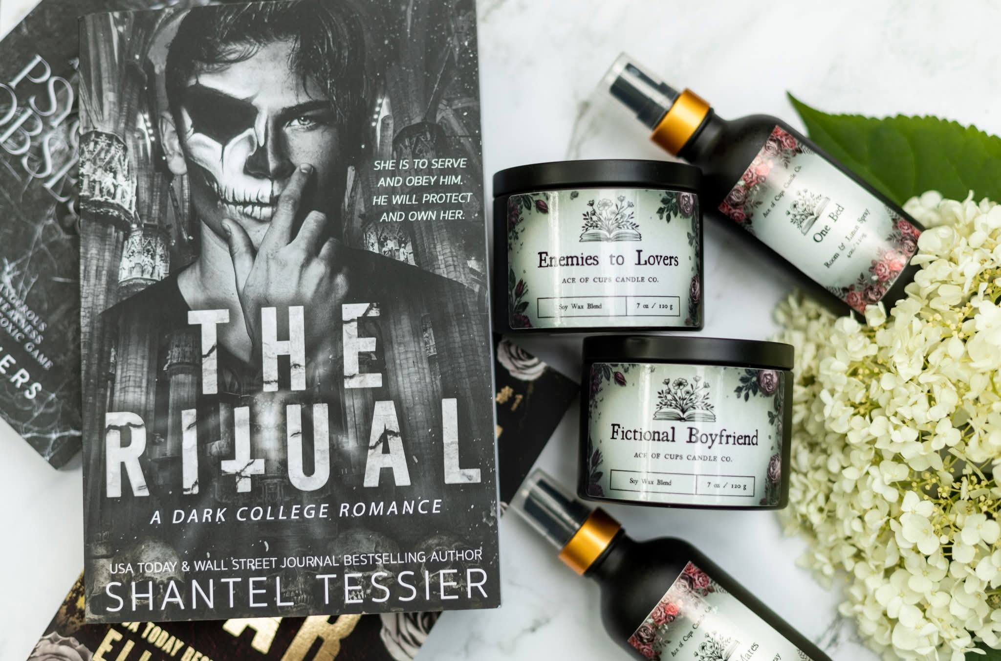 Book cover titled 'The Ritual' by Shantel Tessier, with black and white artwork of a woman, placed next to skincare products and white flowers.