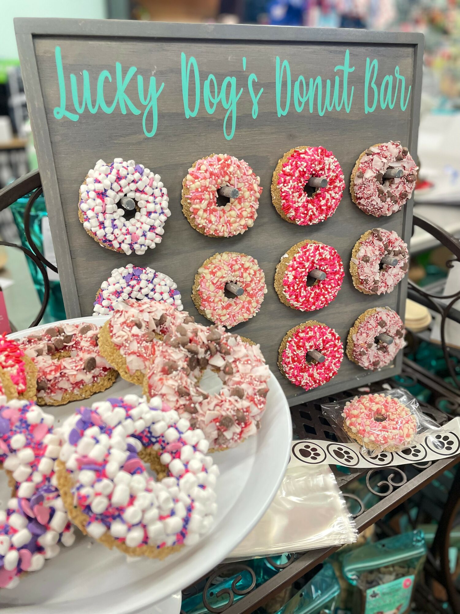 Display of decorated donuts with sprinkles and a sign reading 'Lucky Dog's Donut Bar' in teal text.