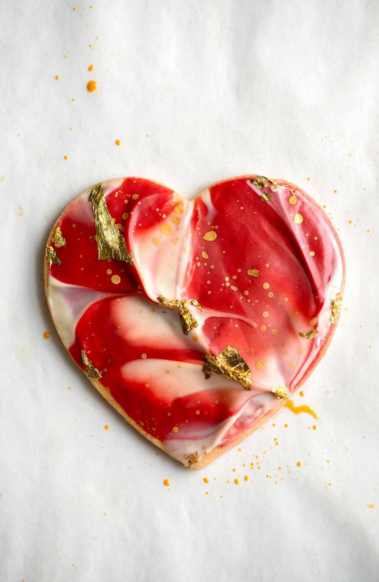 Heart-shaped object with red, white, and gold marbled pattern on white background.