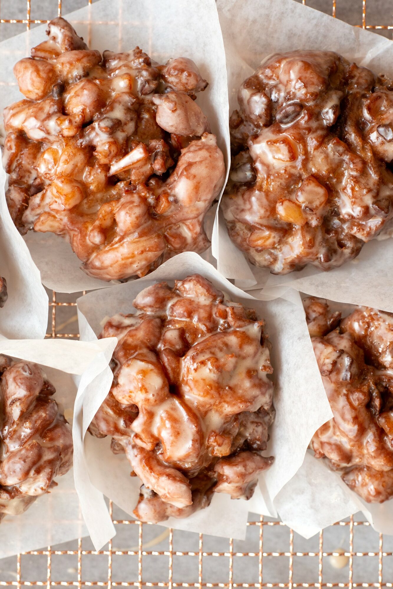 Four pieces of fried chicken on parchment paper, arranged on a wire rack, with a golden-brown crispy coating.