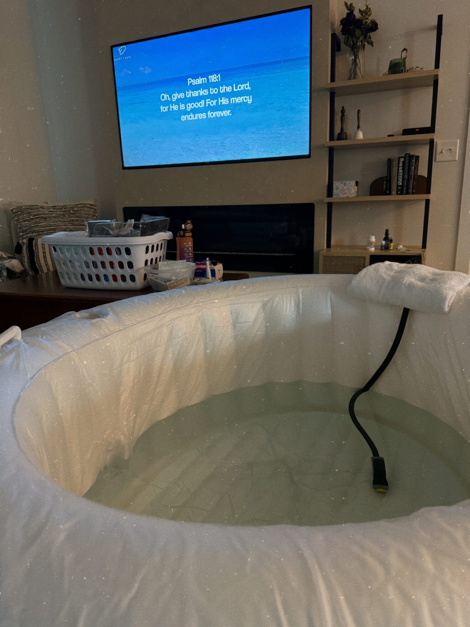 Living room with a TV on the wall, a basket on a table, and an inflatable pool filled with water.