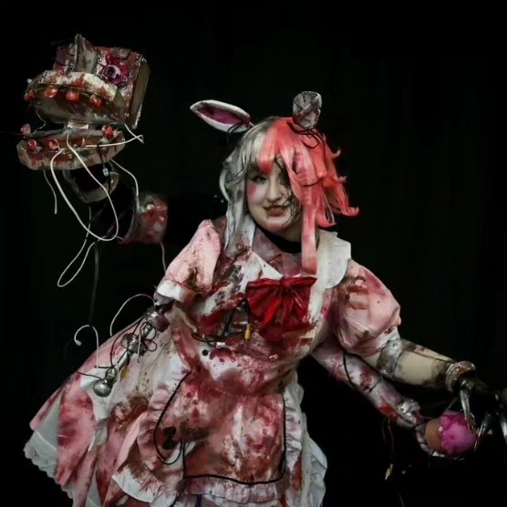 Person dressed as a bunny in a bloody costume holding a bloody prop, with a dark background.