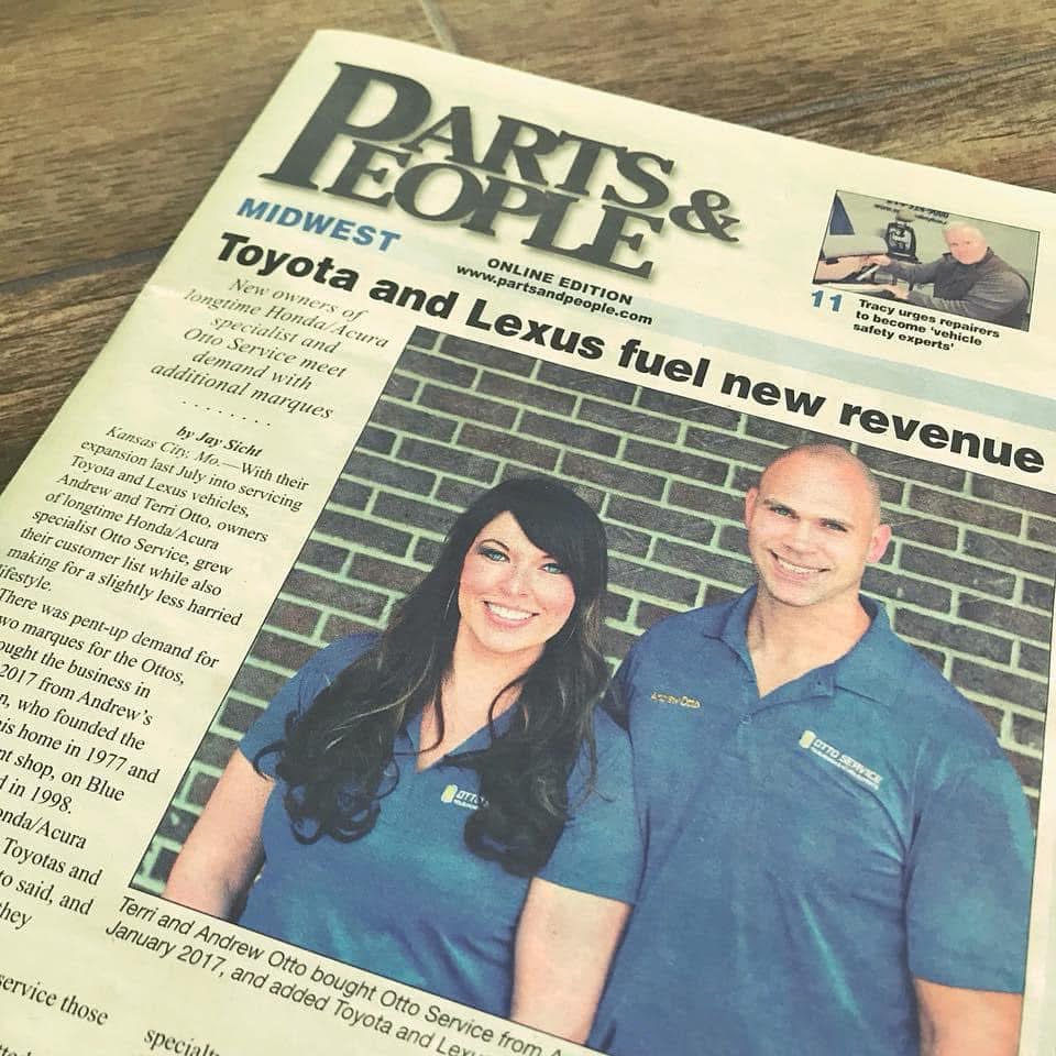 Two people in blue uniforms standing in front of a brick wall, smiling, in a newspaper clipping.